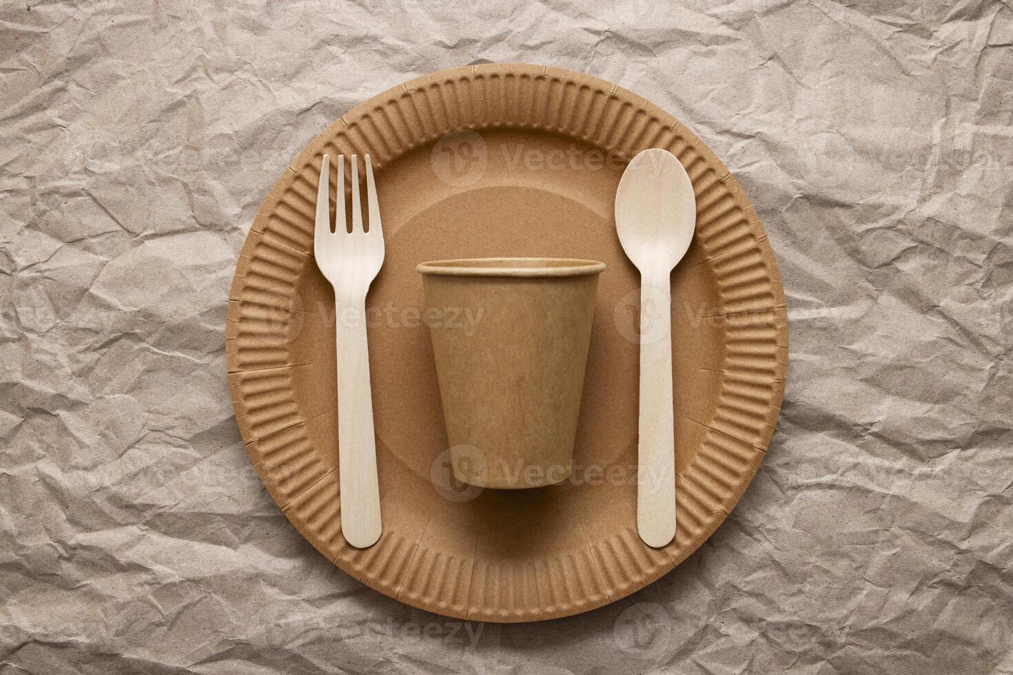 Wooden fork, spoon on cardboard plate on crumpled paper background photo