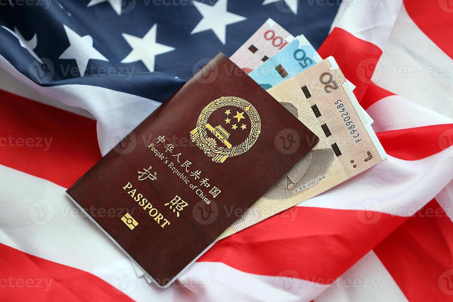 Red passport of People Republic of China and chinese yuan money bills on United States flag photo