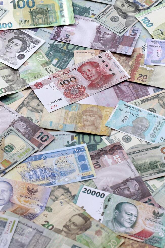 Many banknotes of different currency. Background of big amount of random money bills photo