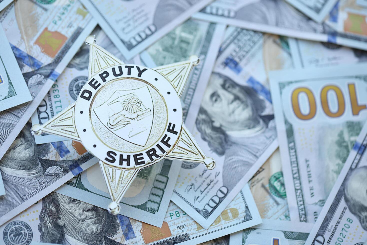 KYIV, UKRAINE - MARCH 9, 2024 US Deputy Sheriff badge on many US hundred dollar bills photo