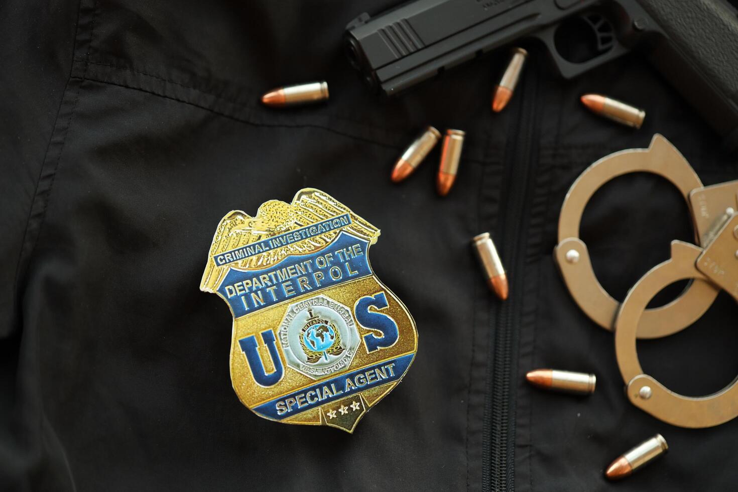 KYIV, UKRAINE - MARCH 9, 2024 US Interpol Special Agent badge on black jacket uniform with gun, bullets and handcuffs photo