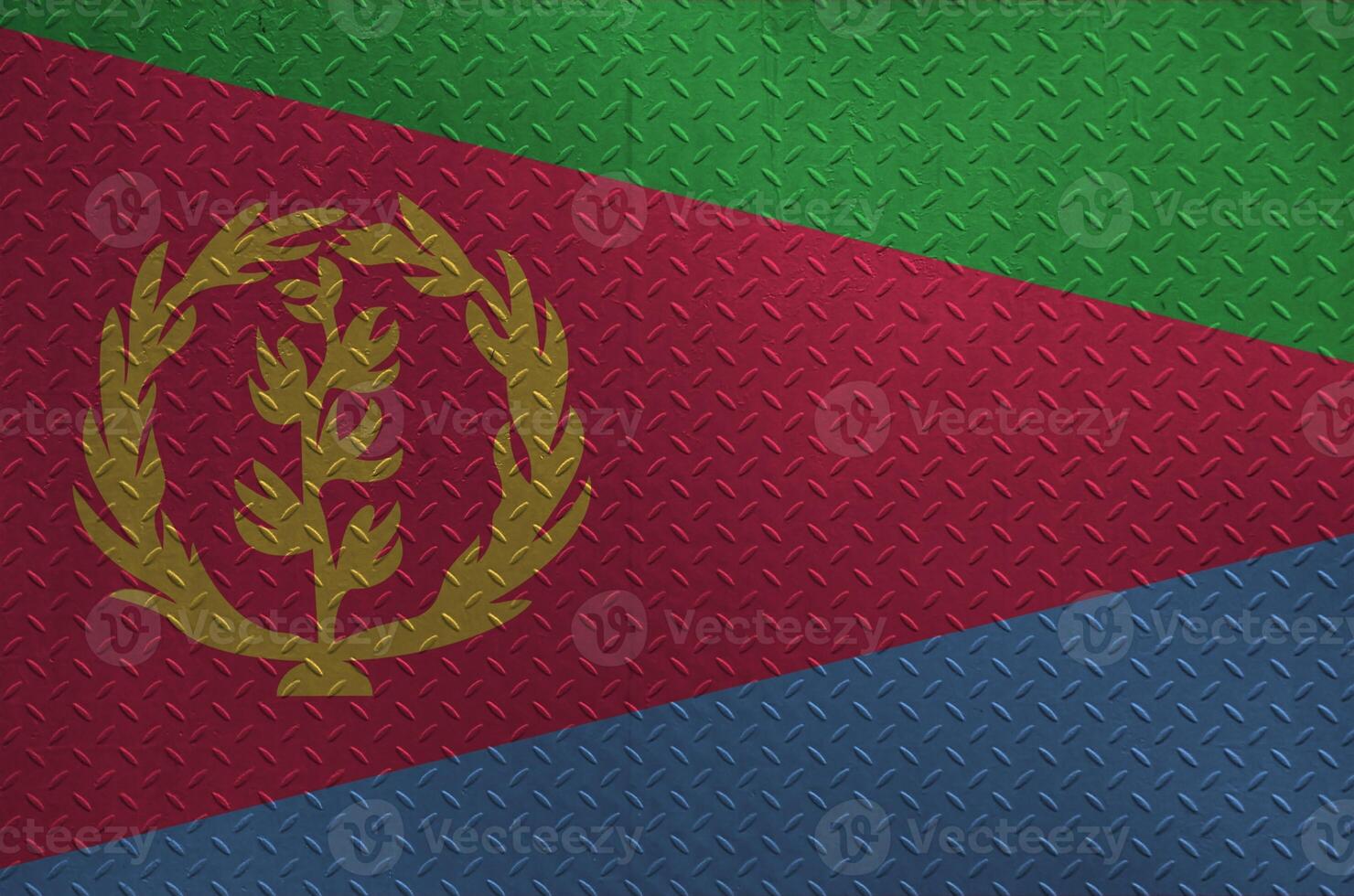 Eritrea flag depicted in paint colors on old brushed metal plate or wall closeup. Textured banner on rough background photo