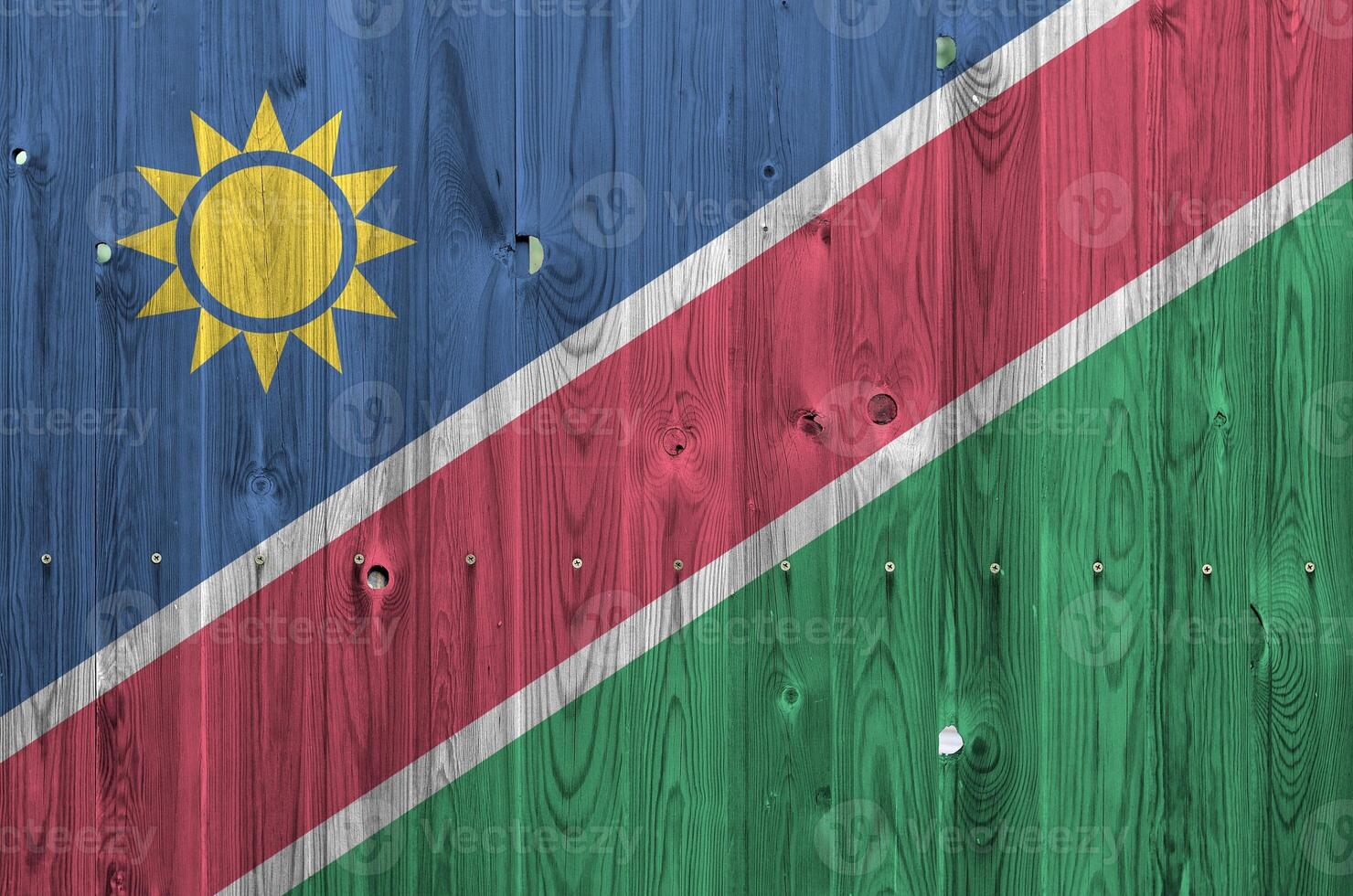 Namibia flag depicted in bright paint colors on old wooden wall. Textured banner on rough background photo