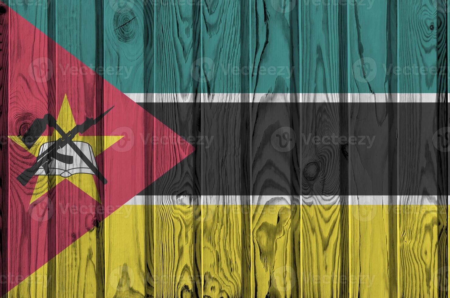 Mozambique flag depicted in bright paint colors on old wooden wall. Textured banner on rough background photo