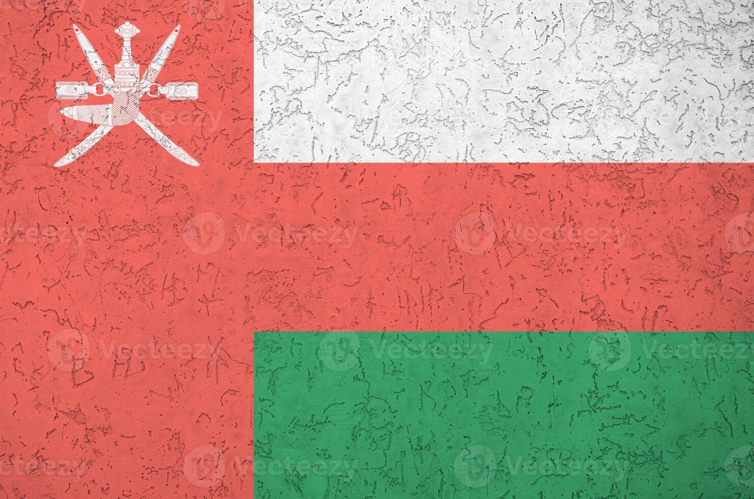 Oman flag depicted in bright paint colors on old relief plastering wall. Textured banner on rough background photo