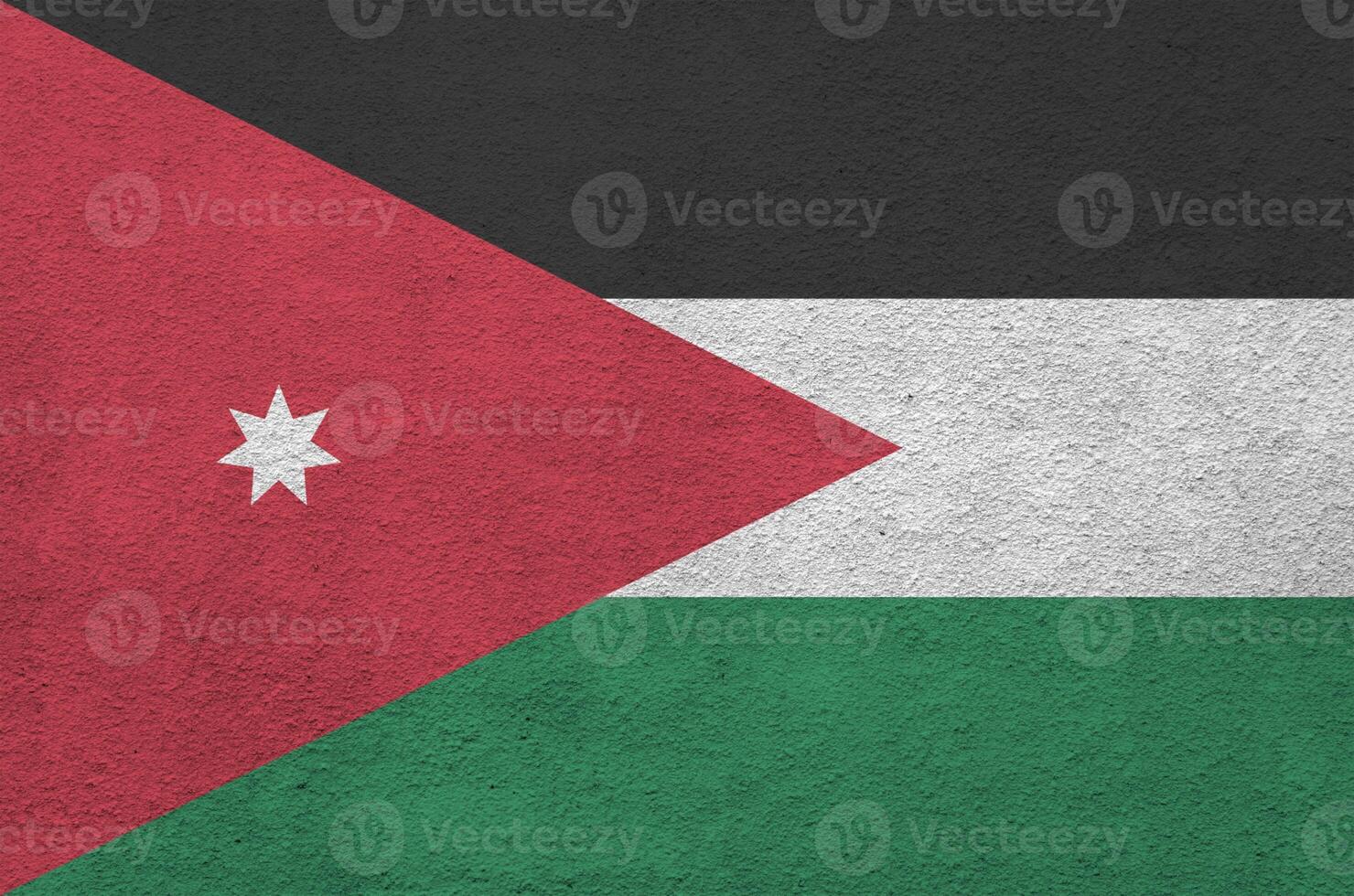 Jordan flag depicted in bright paint colors on old relief plastering wall. Textured banner on rough background photo