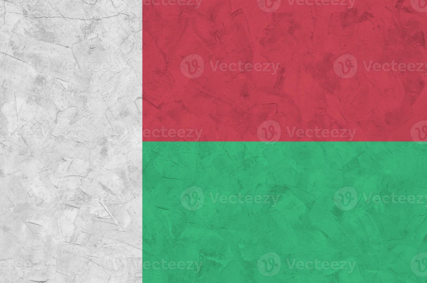 Madagascar flag depicted in bright paint colors on old relief plastering wall. Textured banner on rough background photo