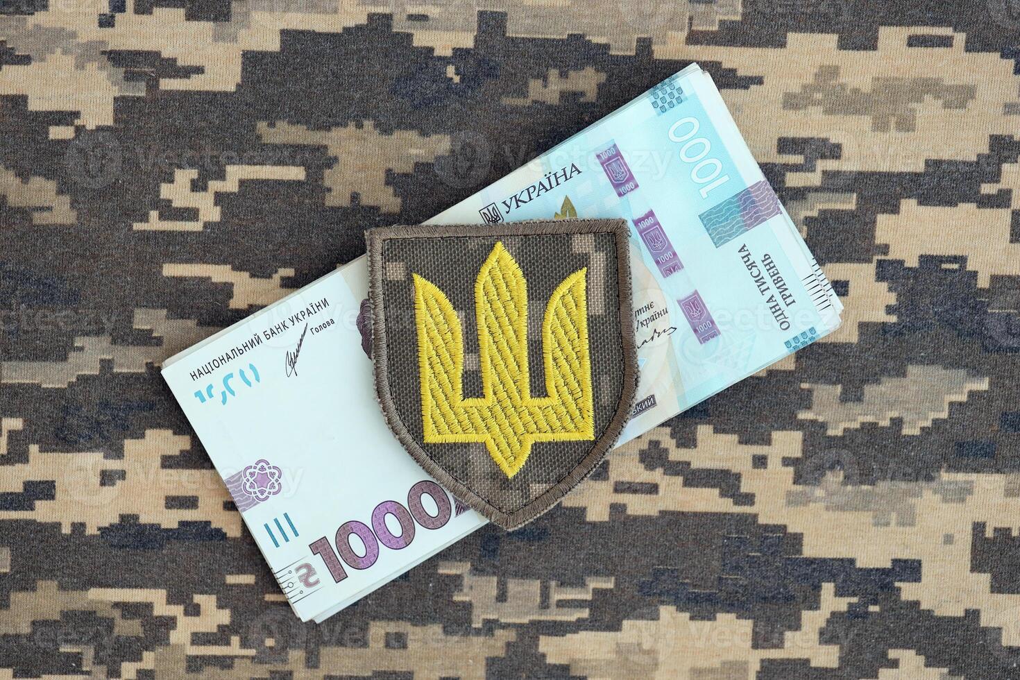 Ukrainian army symbol and bunch of hryvnia bills on military uniform. Payments to soldiers of the Ukrainian army, salaries to the military photo