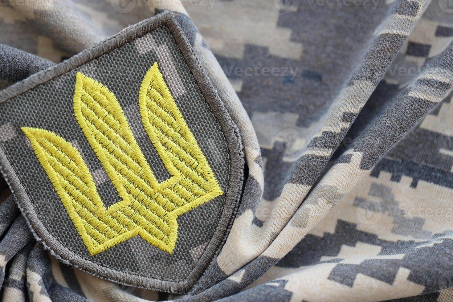 Symbol of Ukrainian army on the camouflage uniform of a Ukrainian soldier. The concept of war in Ukraine, patriotism and protecting your country from occupiers photo