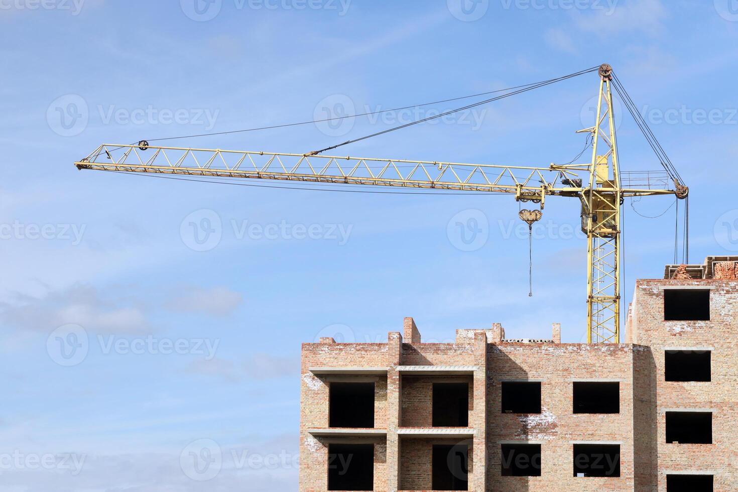 View of a large construction site with buildings under construction and multi-storey residential homes. Tower cranes in action on blue sky background. Housing renovation concept photo