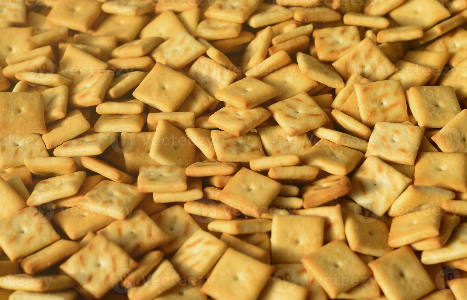 Background texture of small edible squares baked from dough and sprinkled with salt. A lot of salt cracker photo