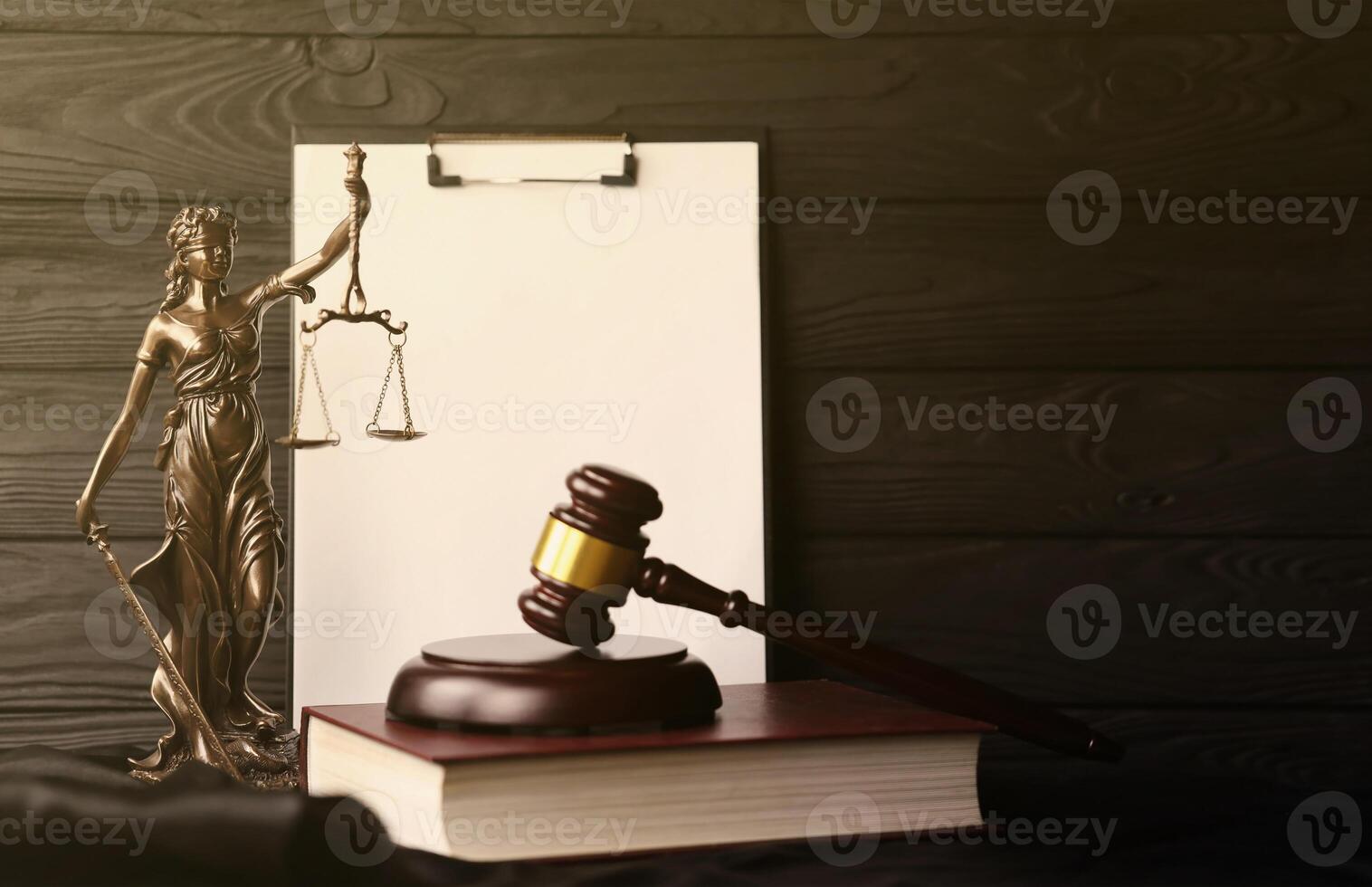 Lady justice or justitia the Roman goddess of Justice. Statue on brown book with judge gavel on blank paper background with copyspace. Concept of judicial trial, courtroom process and lawyers work photo