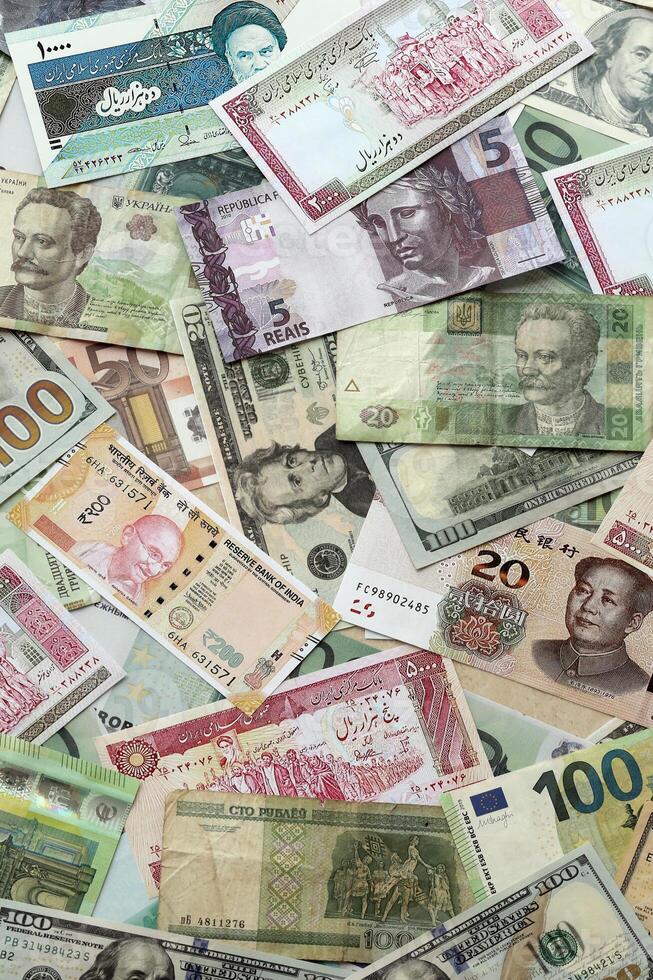 Many banknotes of different currency. Background of big amount of random money bills photo