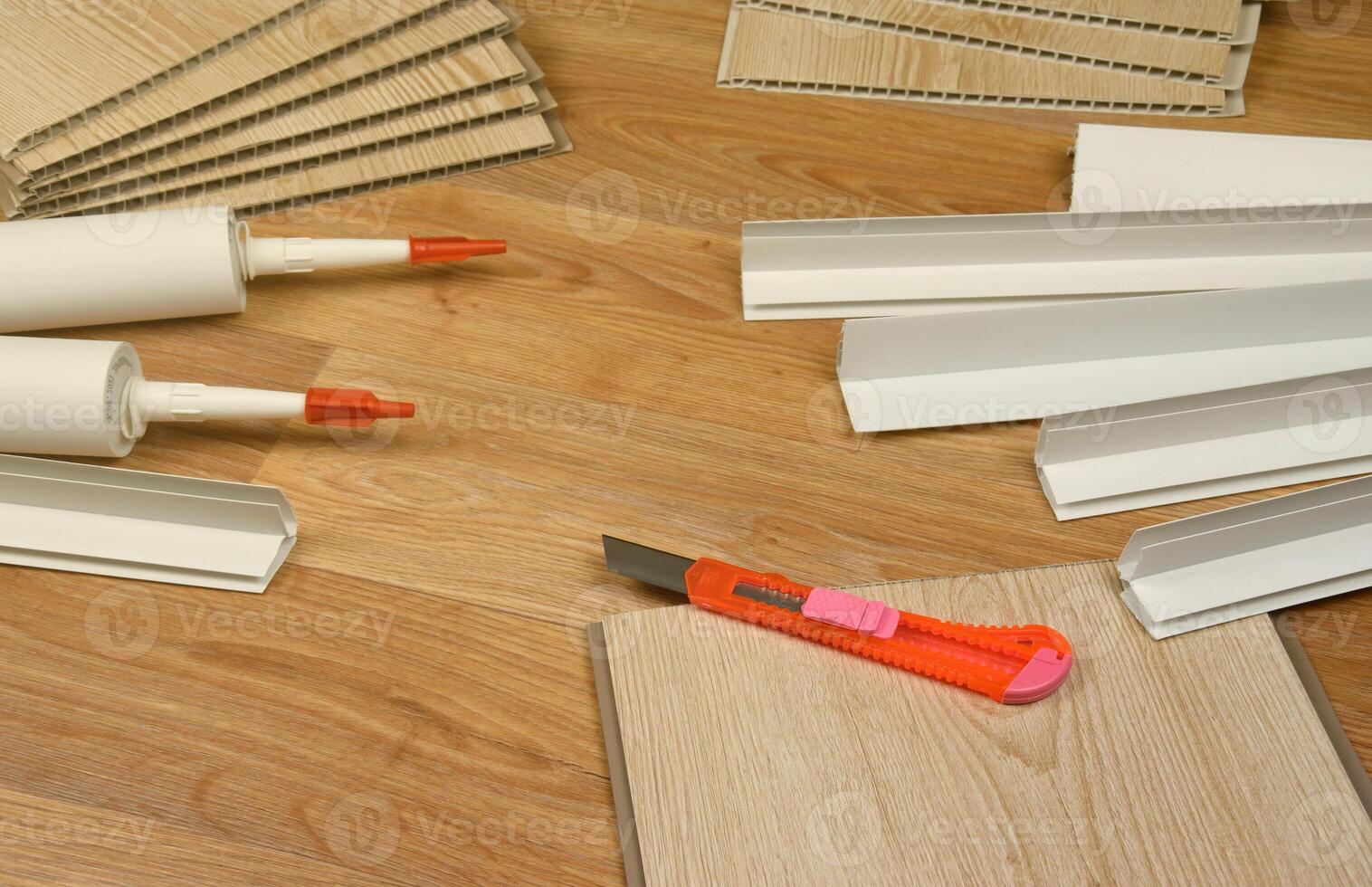 Set of items for PVC ceiling indoor works. Assembly adhesive bottles and PVC panels with plastic corners. Indoor VPC siding kit. Interior renovation works or construction photo