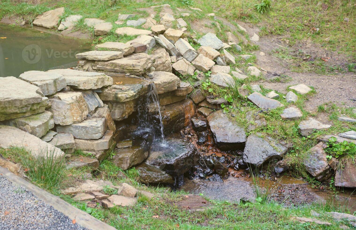 Close up of a small waterfall spilling over moss covered rocks in regional park. Handmade river waterfall photo