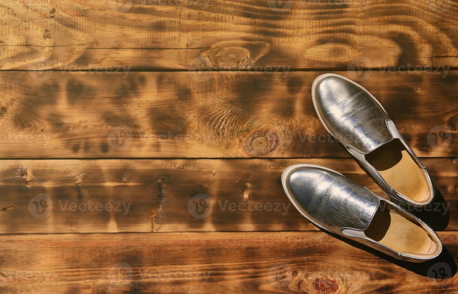 Original shiny shoes in disco style lie on a vintage wooden surface made from fried brown boards. Fashionable clothing retro accessory for discos and parties in the style of the eighties photo