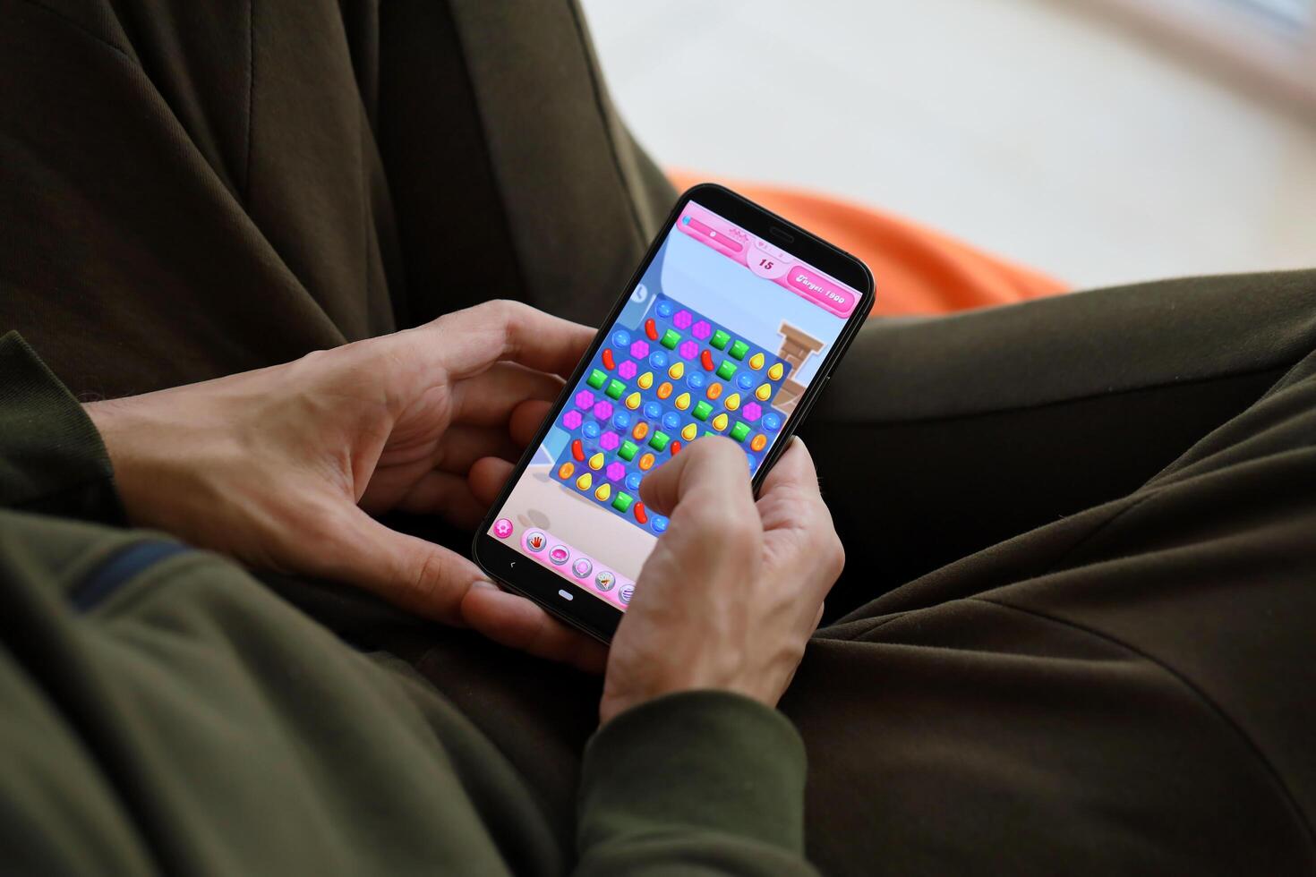 Candy Crush Saga mobile iOS game on iPhone 15 smartphone screen in male hands during mobile gameplay photo