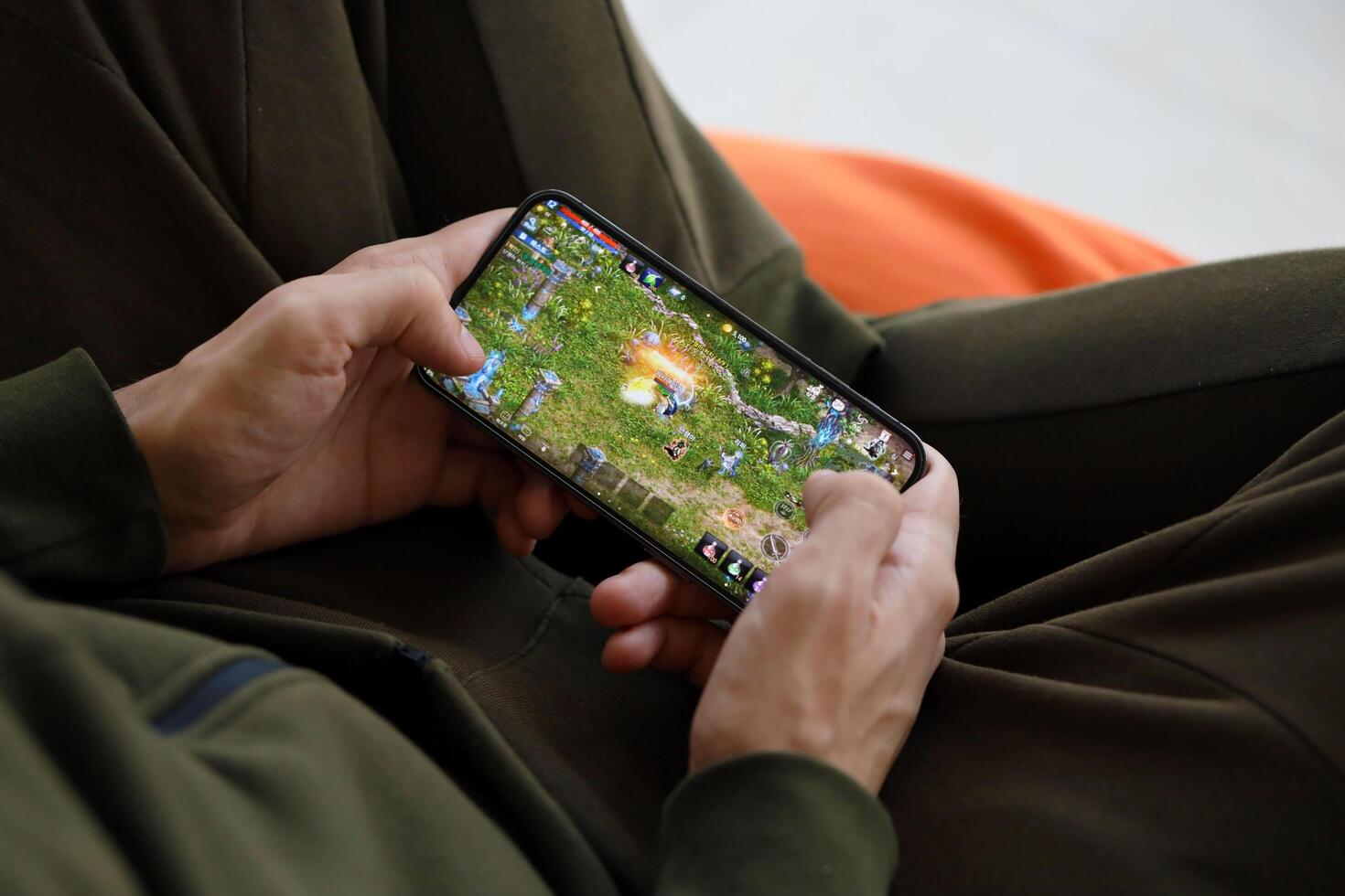 Lineage M mobile iOS game on iPhone 15 smartphone screen in male hands during mobile gameplay photo