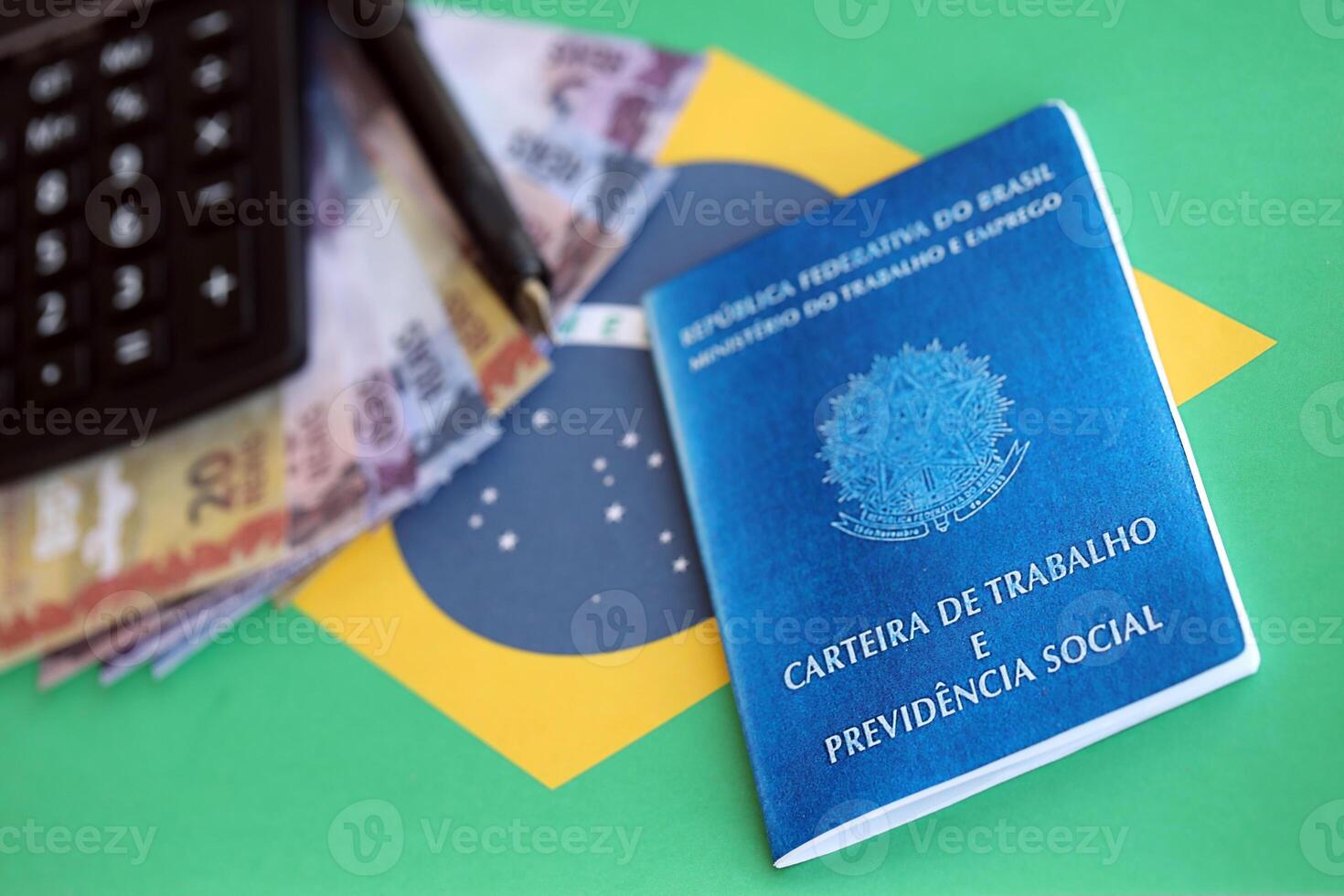 Brazilian work card and social security blue book and reais money bills with calculator and pen on flag of Federative Republic of Brazil photo
