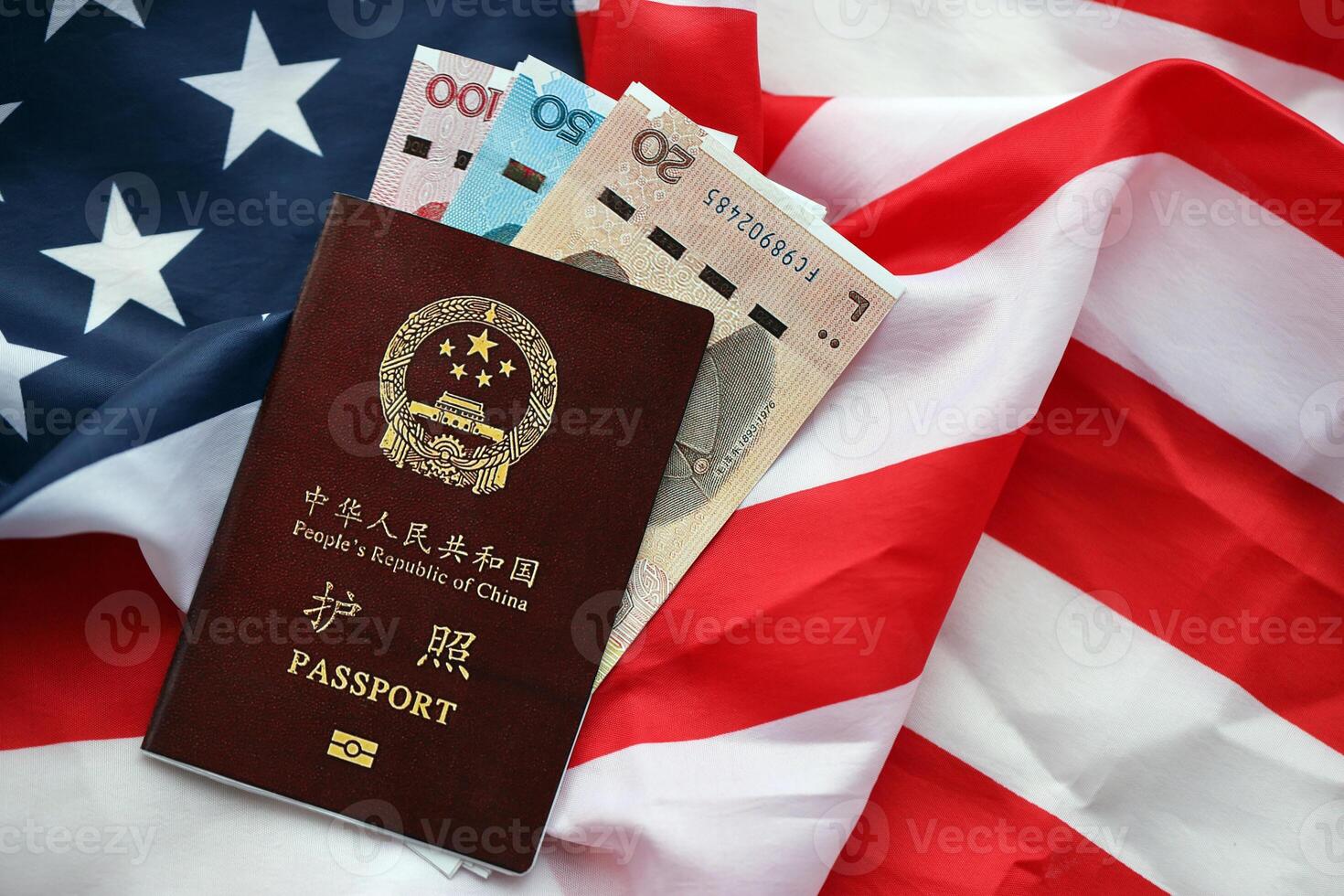 Red passport of People Republic of China and chinese yuan money bills on United States flag photo