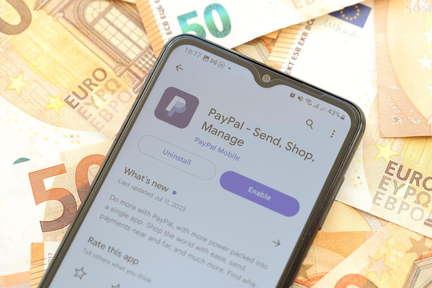 TERNOPIL, UKRAINE - AUGUST 3, 2023 PayPal application on screen on modern smartphone and many bills of euro currency photo