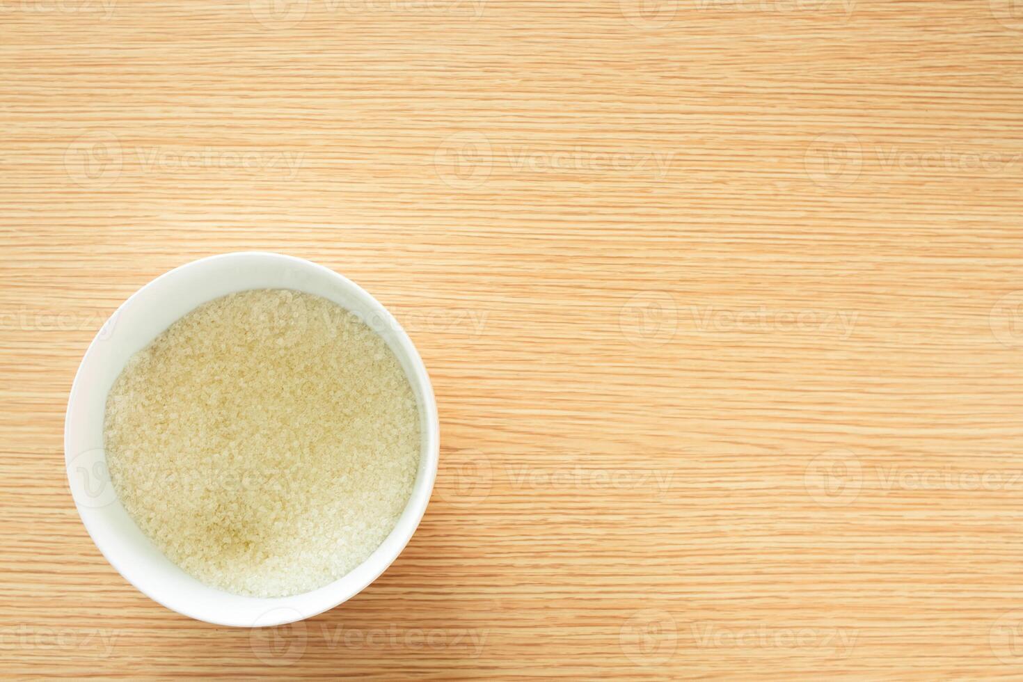 a small bowl filled with granulated sugar on a wooden table photo