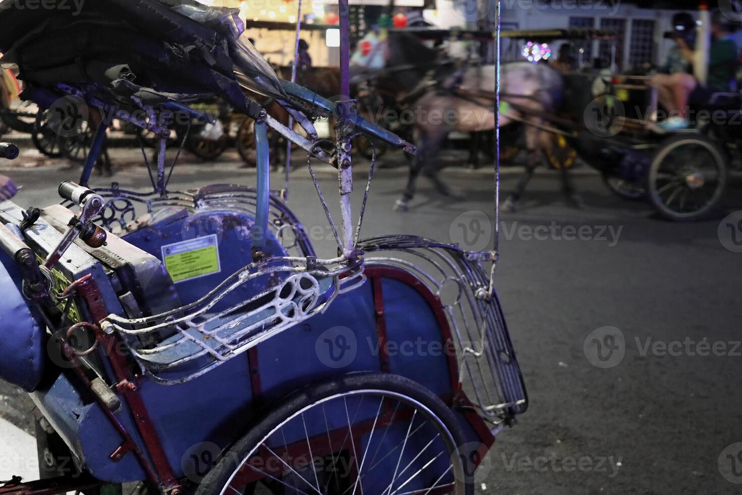 A pedicab or Javanese rickshaw driver is waiting for passengers in the Malioboro area at night photo