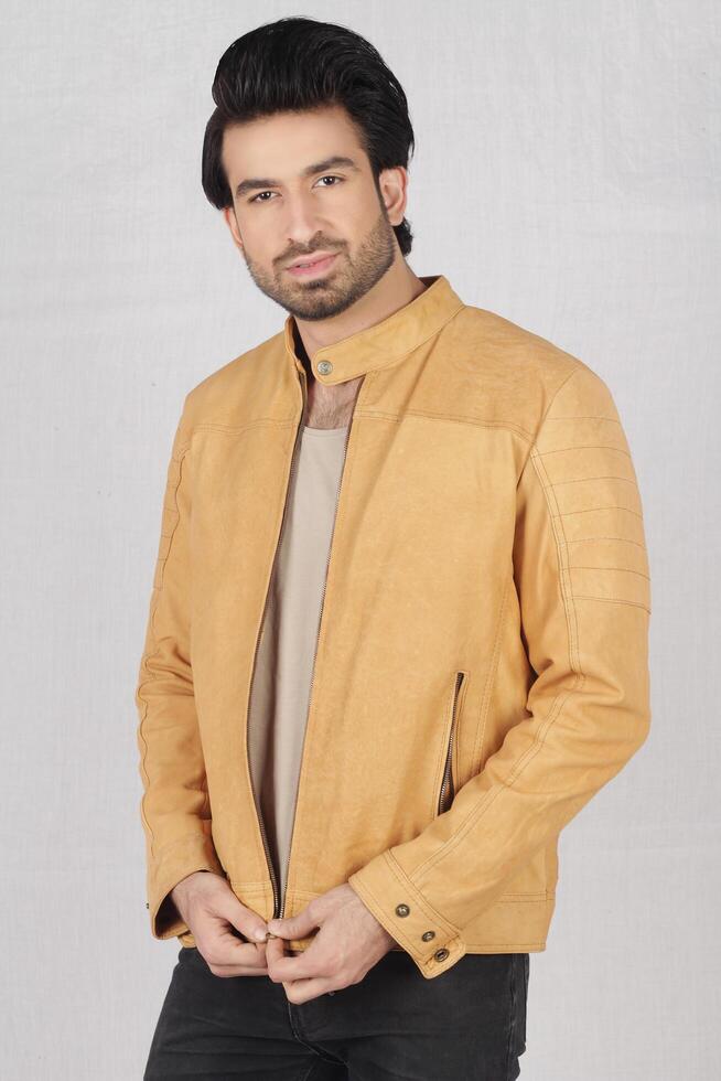 studio shot of young handsome indian man wearing brown leather jacket against white background photo