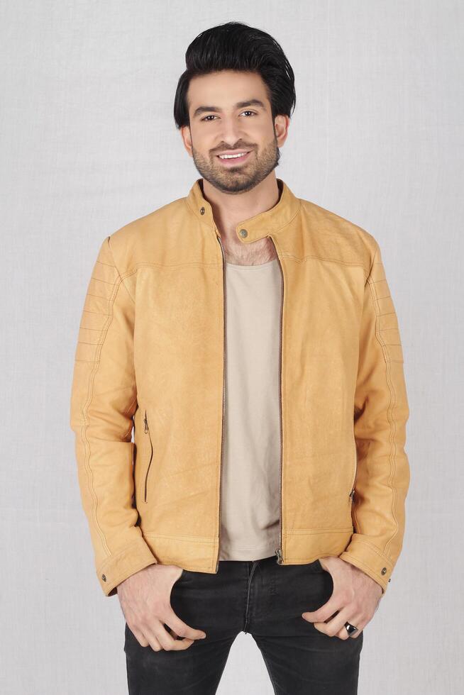 studio shot of young handsome indian man wearing brown leather jacket against white background photo