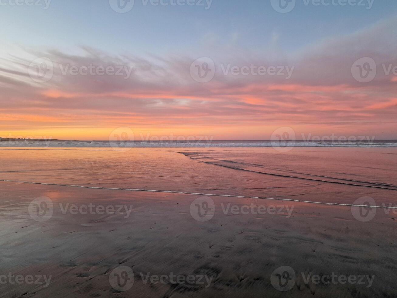 Sunset at Playa de Famara, Lanzarote, paints the sky with vibrant hues, casting a mesmerizing glow over the horizon. Breathtaking sight that captures the essence of tranquility and natural beauty. photo