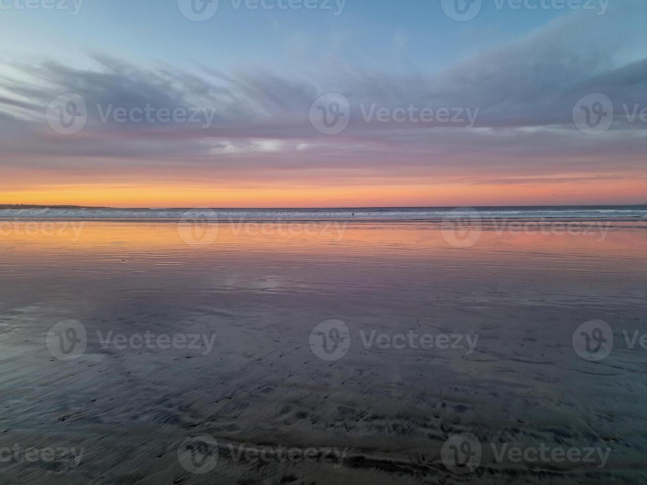 Sunset at Playa de Famara, Lanzarote, paints the sky with vibrant hues, casting a mesmerizing glow over the horizon. Breathtaking sight that captures the essence of tranquility and natural beauty. photo