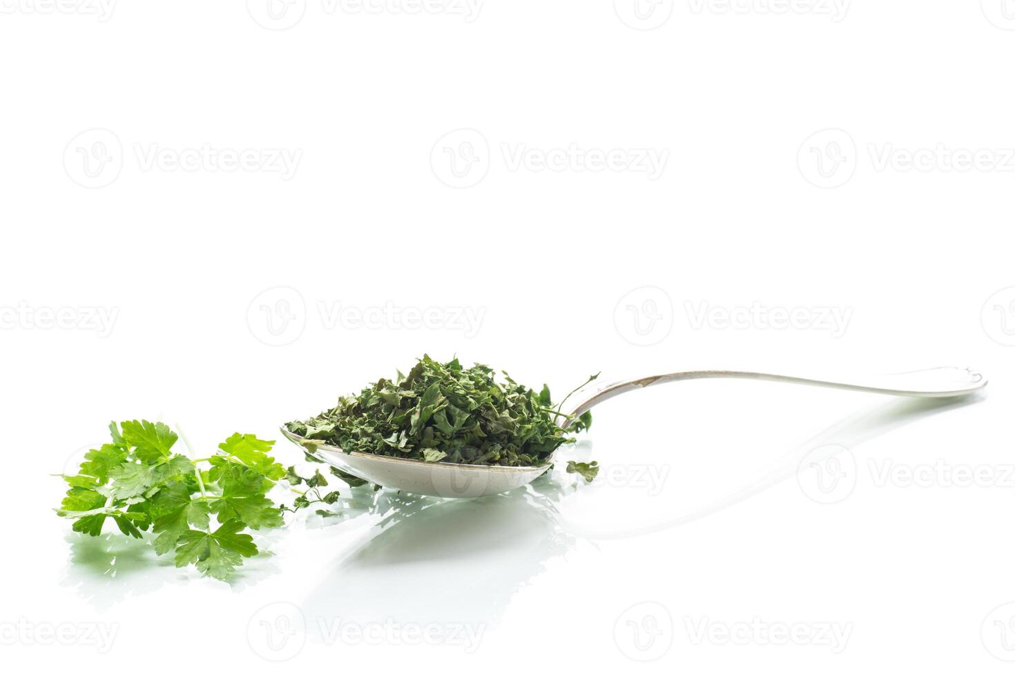 dried parsley in a spoon next to fresh herbs. photo