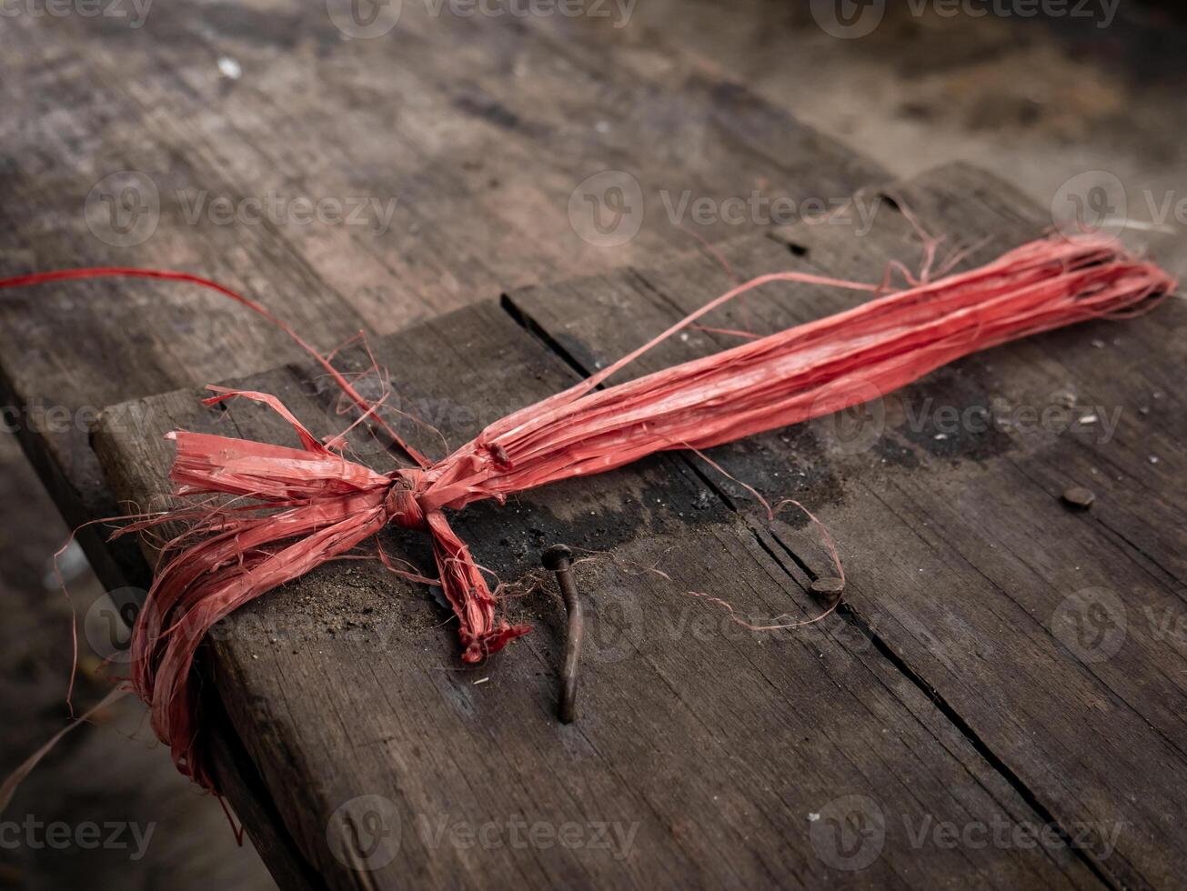 red and broken raffia rope tied to a wooden chair photo