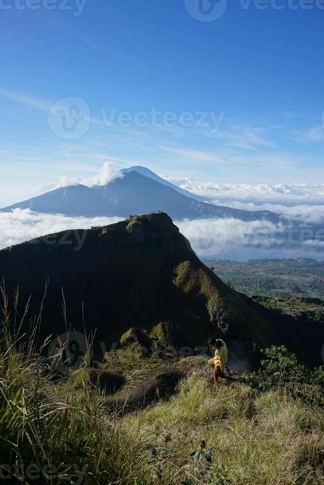 Peak Paradise, Asian Model on Mount Batur Summit with Ocean of Clouds under Azure Sky photo