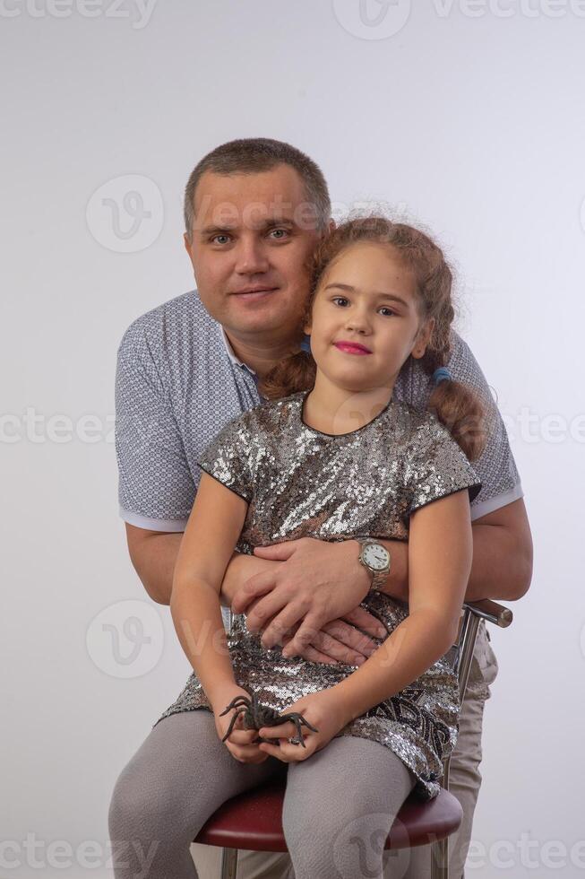 Portrait of lovely daughter smiling and sitting on the neck of her handsome father isolated over gray background 1 photo