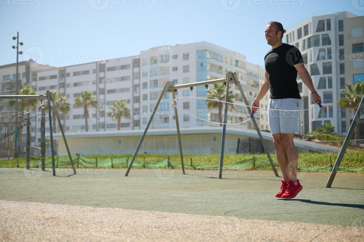 Young athletic man exercising with a jumping skipping rope in urban environment. photo