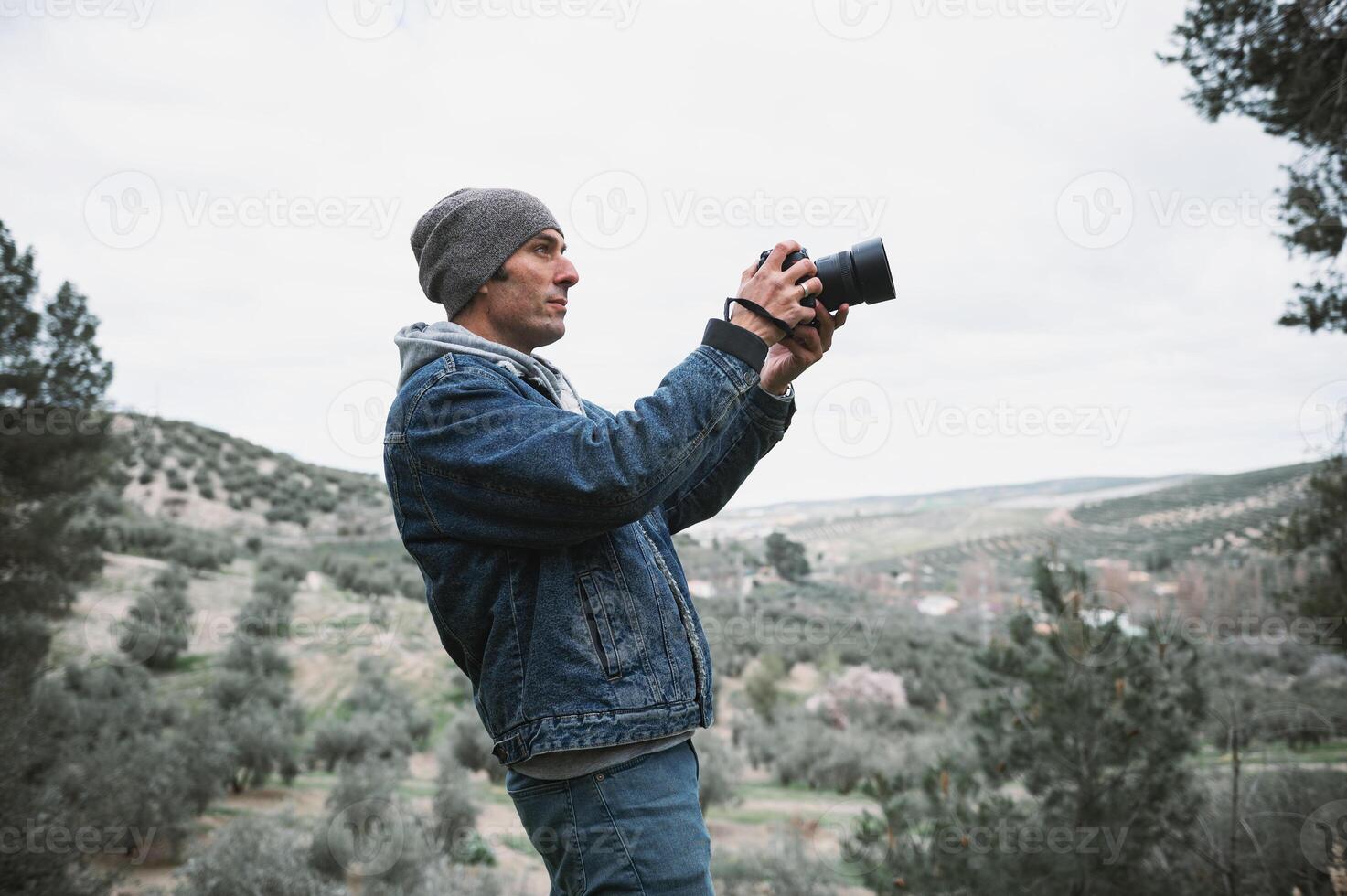 Young traveler photographer man using a camera, taking pictures of mountains while trekking in the early spring nature photo