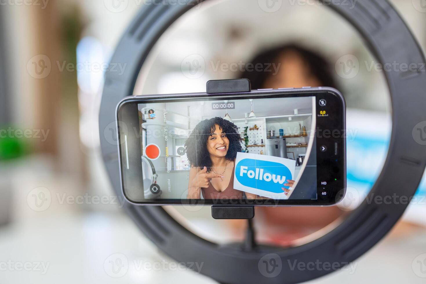 Young female influencer using her smart phone for filming a vlog post. photo