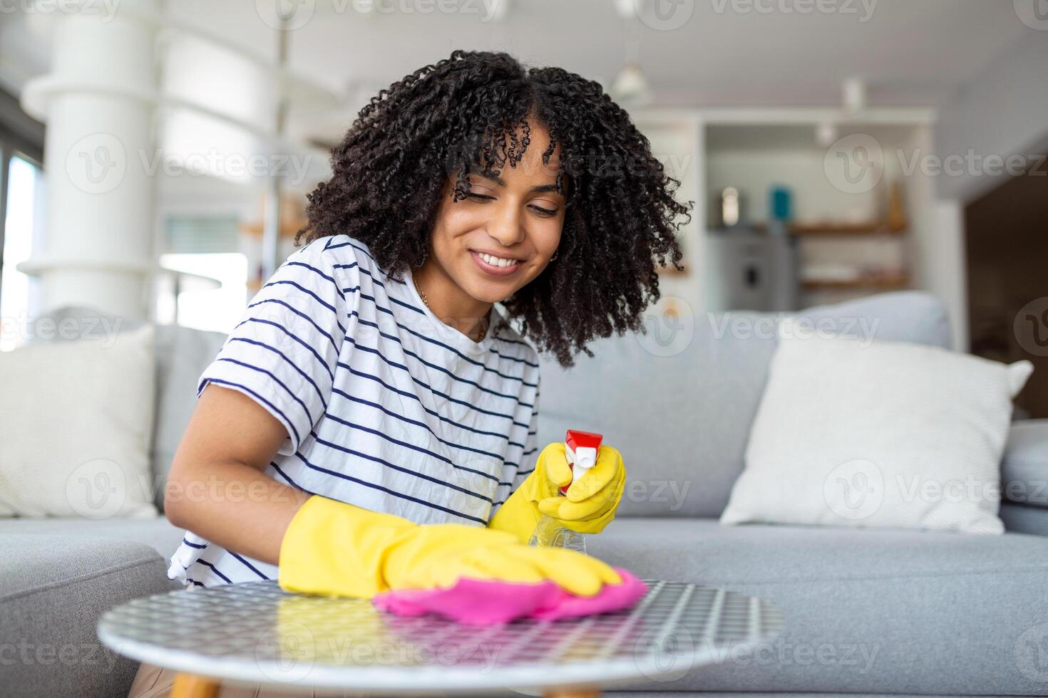 Young beautiful woman tidying up the living room and wiping the dining table surface with a cloth. photo