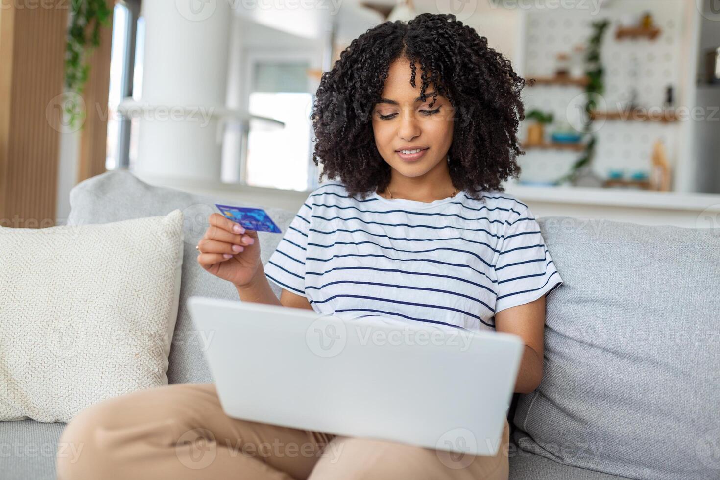 Young Woman On Sofa Shopping Online With Debit Card. Beautiful girl using laptop computer for online shopping at home photo