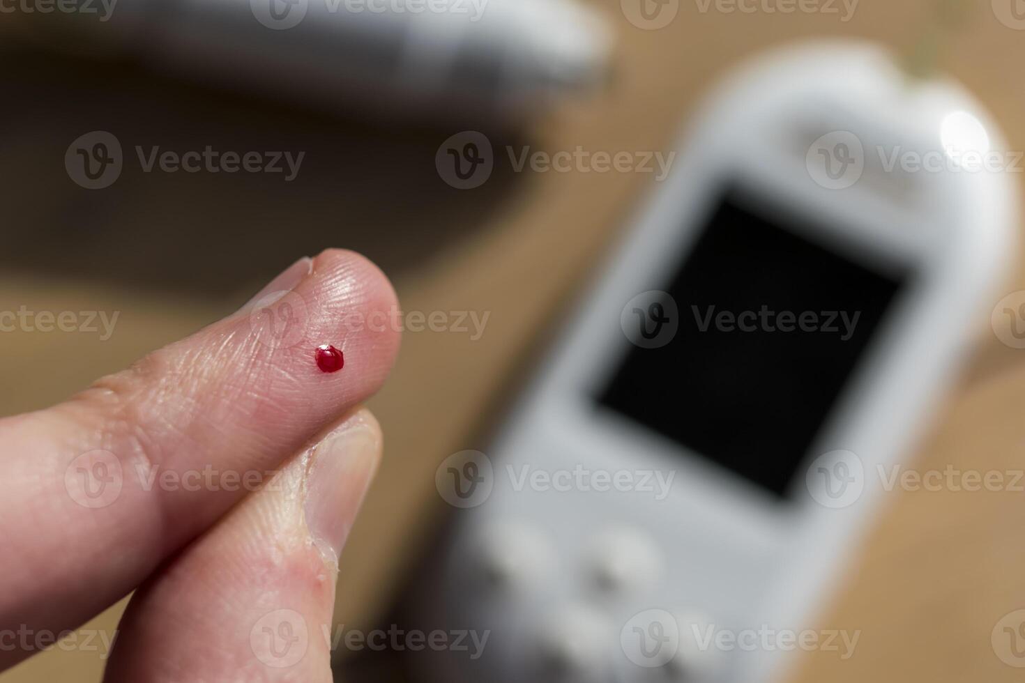 Woman pricking her finger to check blood glucose level with glucometer, test blood glucose for diabetes photo