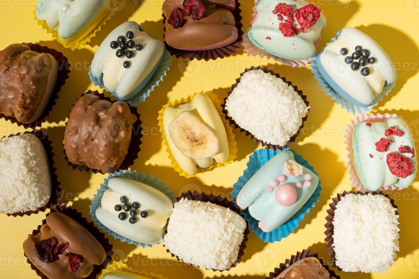 Set of different macaroons on yellow background top view, flat lay photo