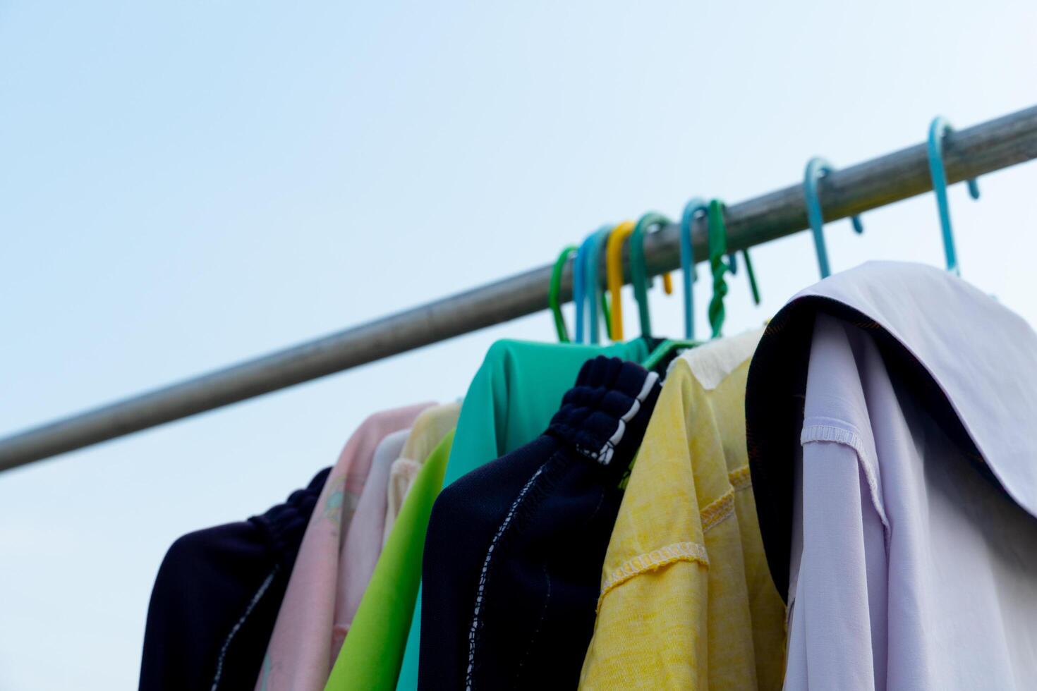 Colorful clothes hanging with hangers. Clothes hanger hanging on iron railing. under the clear sky. photo