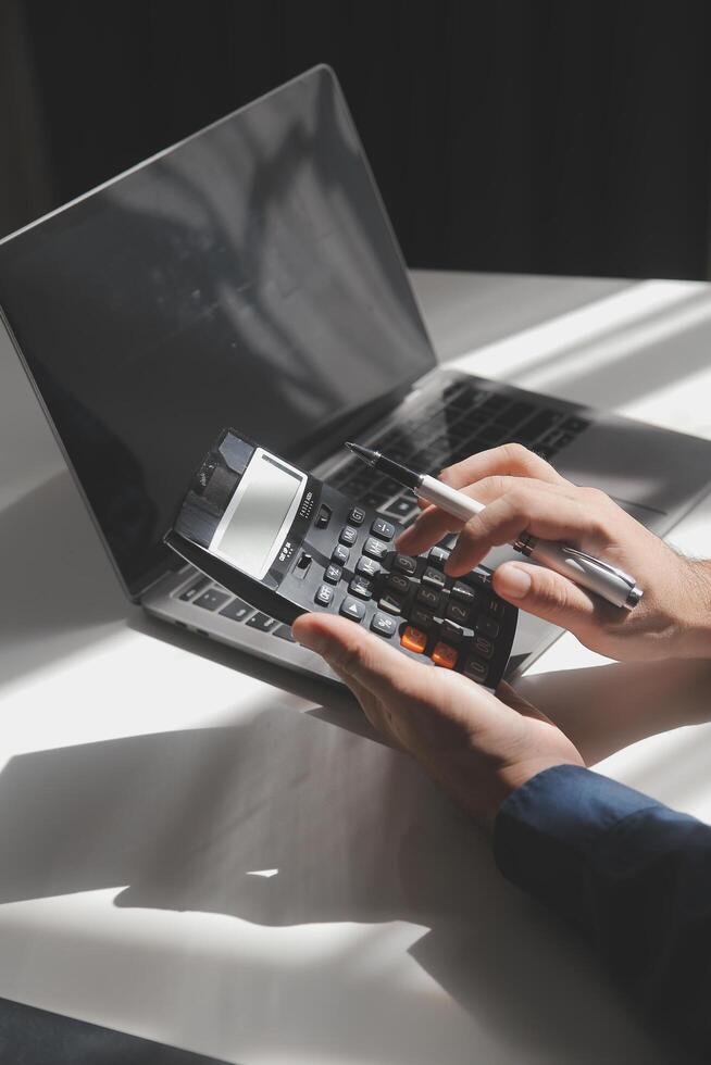 businessman working on desk office with using a calculator to calculate the numbers, finance accounting concept photo