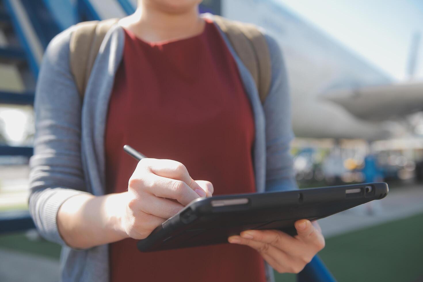 Blonde female tourist checking incoming notification on smartphone sitting on seat of airplane with netbook.Young businesswoman share media from telephone on laptop computer during plane flight photo