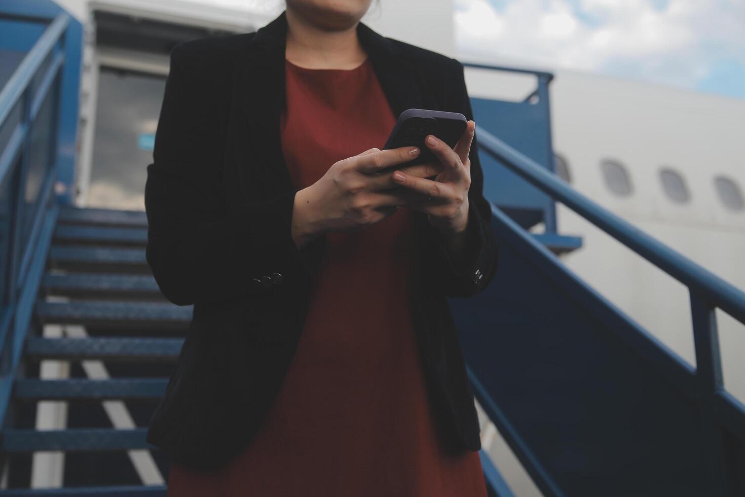 Young asian woman in international airport, using mobile smartphone and checking flight at the flight information board photo