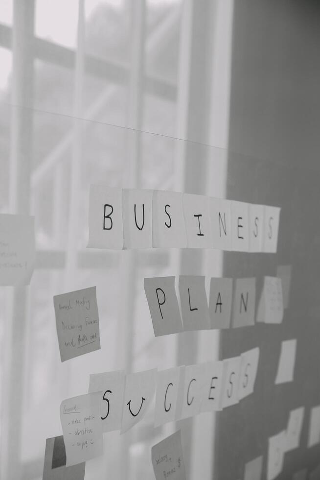 joven creativo equipo profesional utilizando enviar eso notas en vaso pared a escritura estrategia negocio plan a desarrollo crecer a éxito. foto