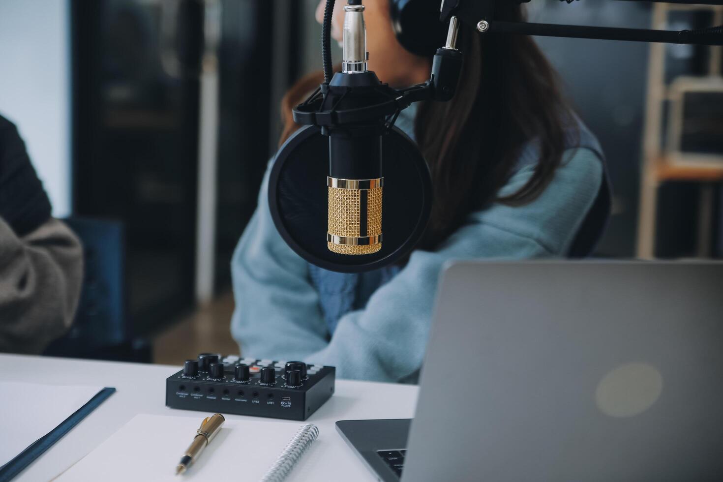 Woman recording a podcast on her laptop computer with headphones and a microscope. Female podcaster making audio podcast from her home studio. photo