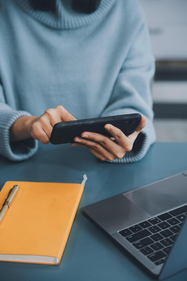 Happy pretty millennial Indian girl relaxing at home, resting in armchair, typing on smartphone, using online app, software, shopping on Internet, making video call. Mobile phone communication photo