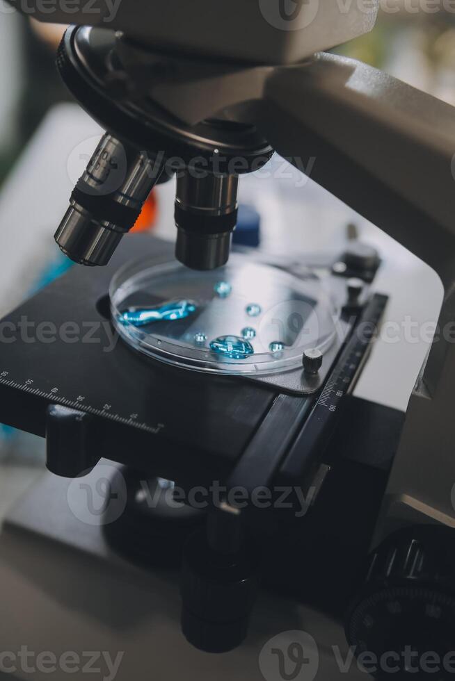 equipo científico de investigación bioquímica que trabaja con microscopio para el desarrollo de vacunas contra el coronavirus en laboratorios de investigación farmacéutica, enfoque selectivo foto